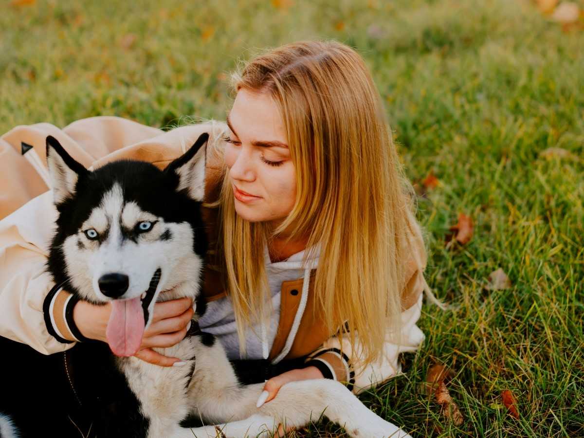 lady lying on grass with husky